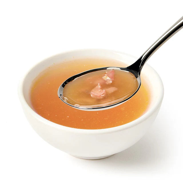 Canagan Tuna Soup for Cats served in a white bowl, showing the clear broth texture and tender chicken pieces on a spoon.