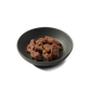 Chunks of Dinky Dog Turkey & Pheasant 85g wet dog food served in a dark bowl, highlighting its natural texture and ingredients.