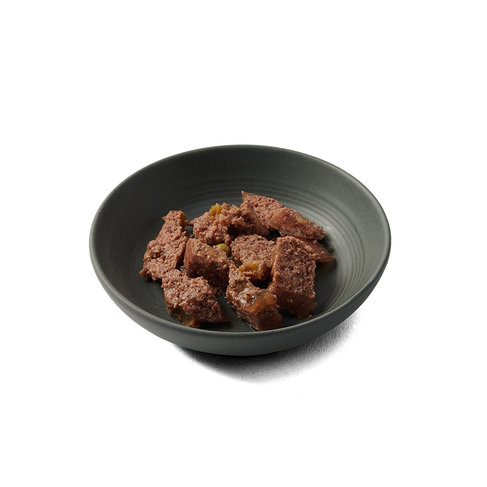 Chunks of Dinky Dog Lamb & Apple 85g wet dog food served in a dark bowl, showcasing its natural texture and nutritious ingredients.