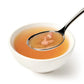 Canagan Tuna Soup for Cats served in a white bowl, showing the clear broth texture and tender chicken pieces on a spoon.
